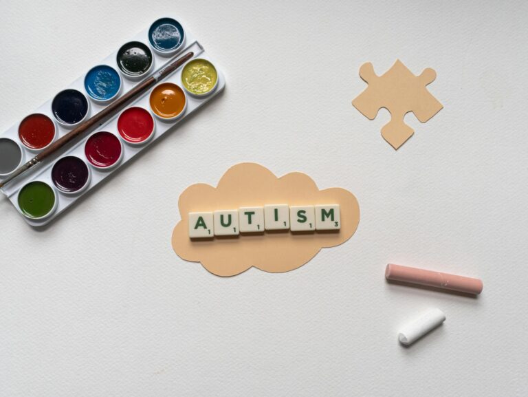 Flat lay of autism awareness concept with art materials and puzzle piece.