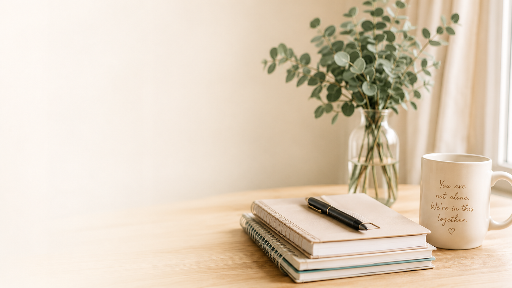Notebooks, eucalyptus and a mug that reads You are not alone. We are in this together.